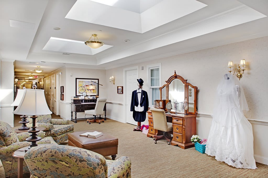 A spacious living room with comfortable seating and a decorative dressing table, featuring a mannequin dressed in formal attire.