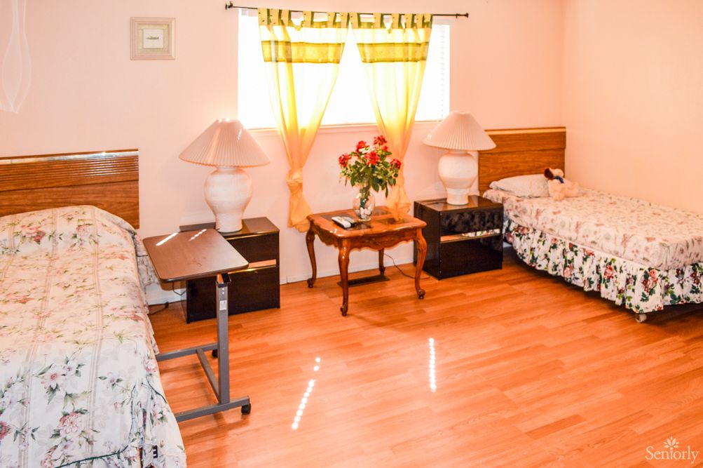 A cozy bedroom with two twin beds, wooden flooring, and floral decor.