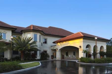 A large residential building with a red-tiled roof and landscaped surroundings.