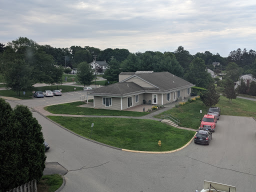 A view of a building situated in a peaceful residential neighborhood with a cloudy sky overhead.