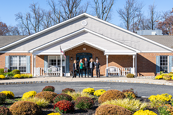 A group of people standing in front of a building surrounded by landscaped gardens.