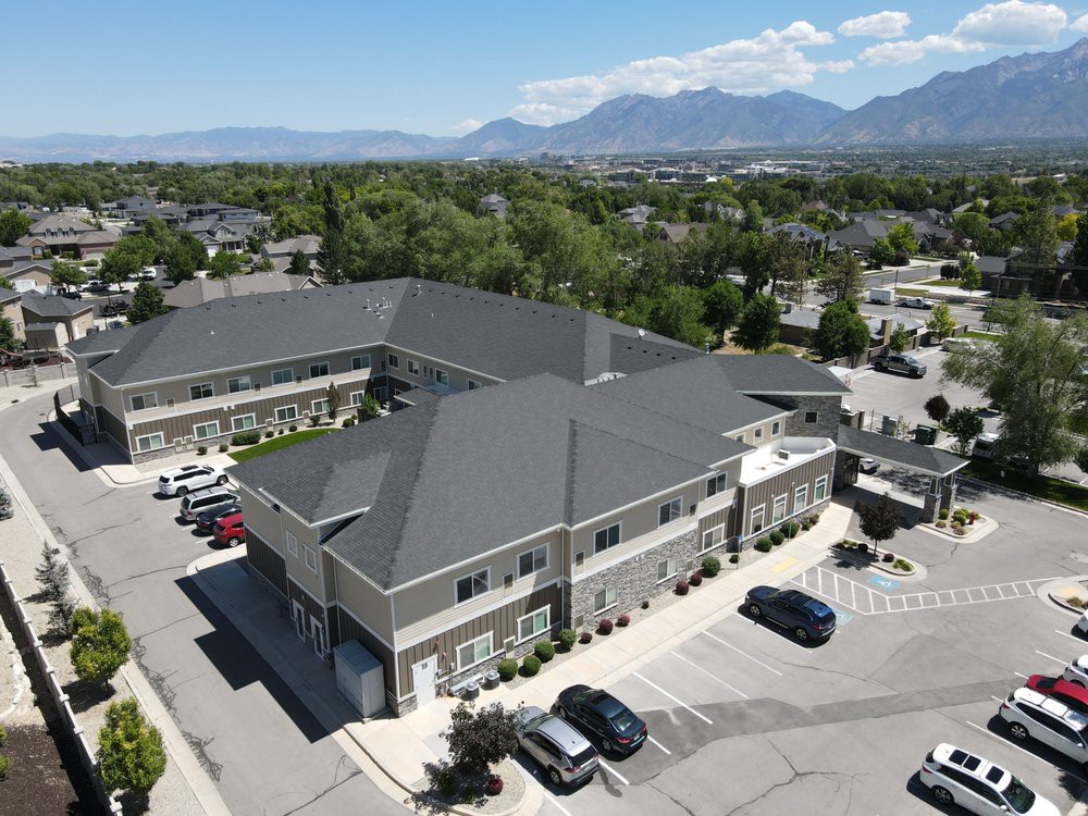 Aerial view of a suburban building with parking lot and mountain backdrop.