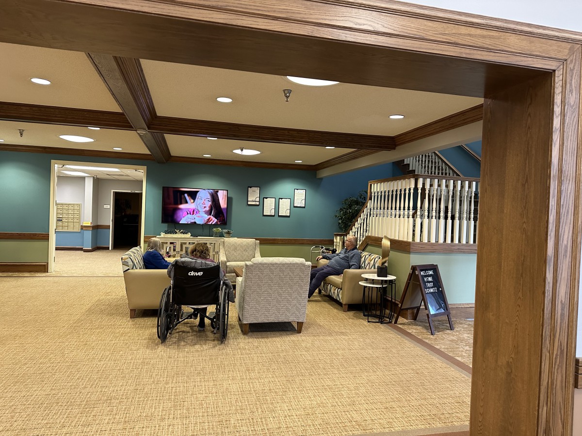 A cozy lounge area with comfortable seating, a television, and a staircase in the background.