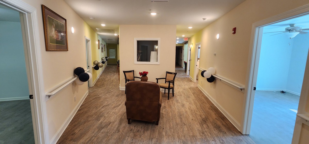 A cozy hallway with seating area featuring chairs and a table, accentuated by warm lighting.