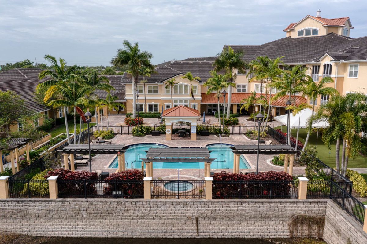 A luxurious resort featuring a central swimming pool surrounded by palm trees and elegant architecture.