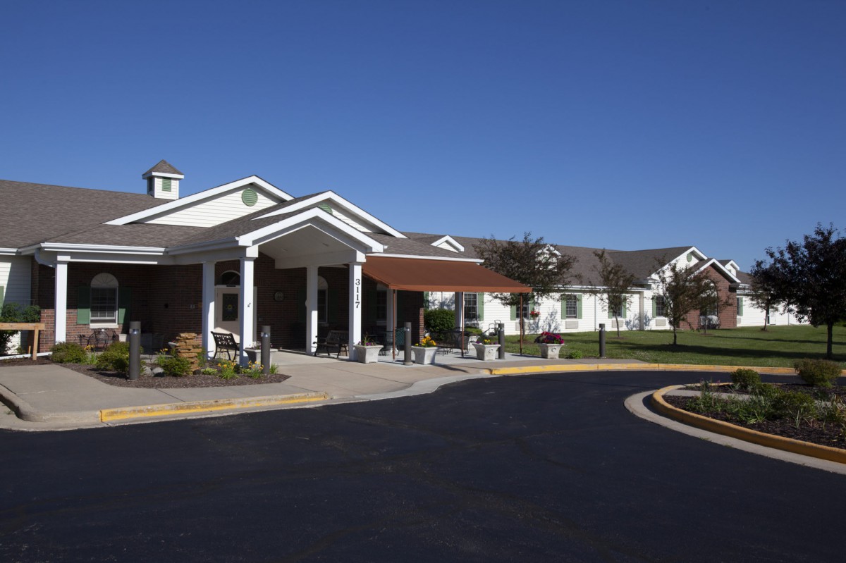 A large building with a covered entrance and driveway under a clear blue sky.
