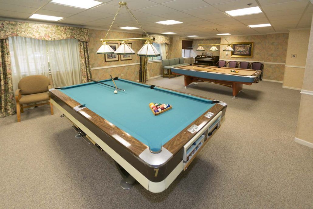 A spacious game room featuring two pool tables with overhead lighting.