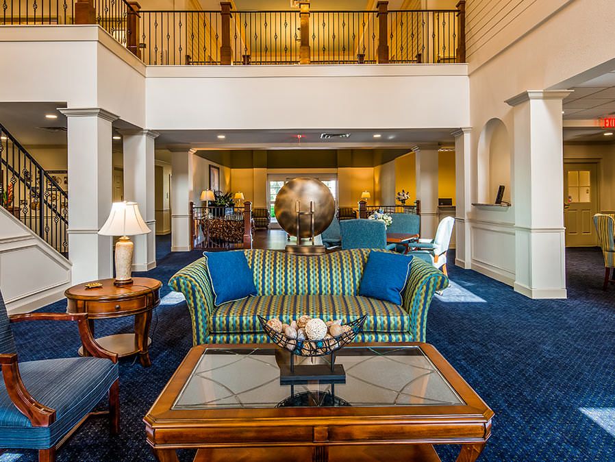 A spacious living room with elegant furniture and decor, featuring a striped sofa, a glass coffee table, and a decorative globe.