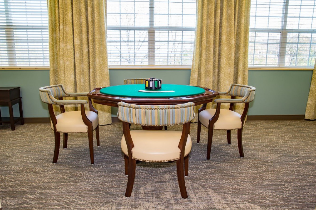 A cozy poker table setup with four chairs in a well-lit room.