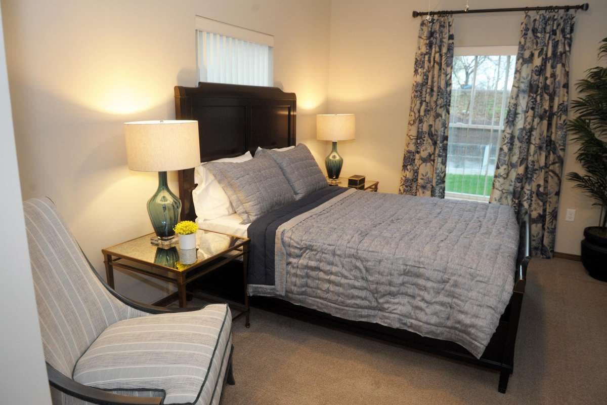 A cozy and well-decorated bedroom with a neatly made bed, stylish lamps on bedside tables, and patterned curtains.