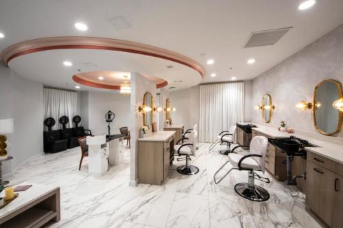 A modern and stylish beauty salon interior with comfortable chairs, mirrors, and elegant lighting.