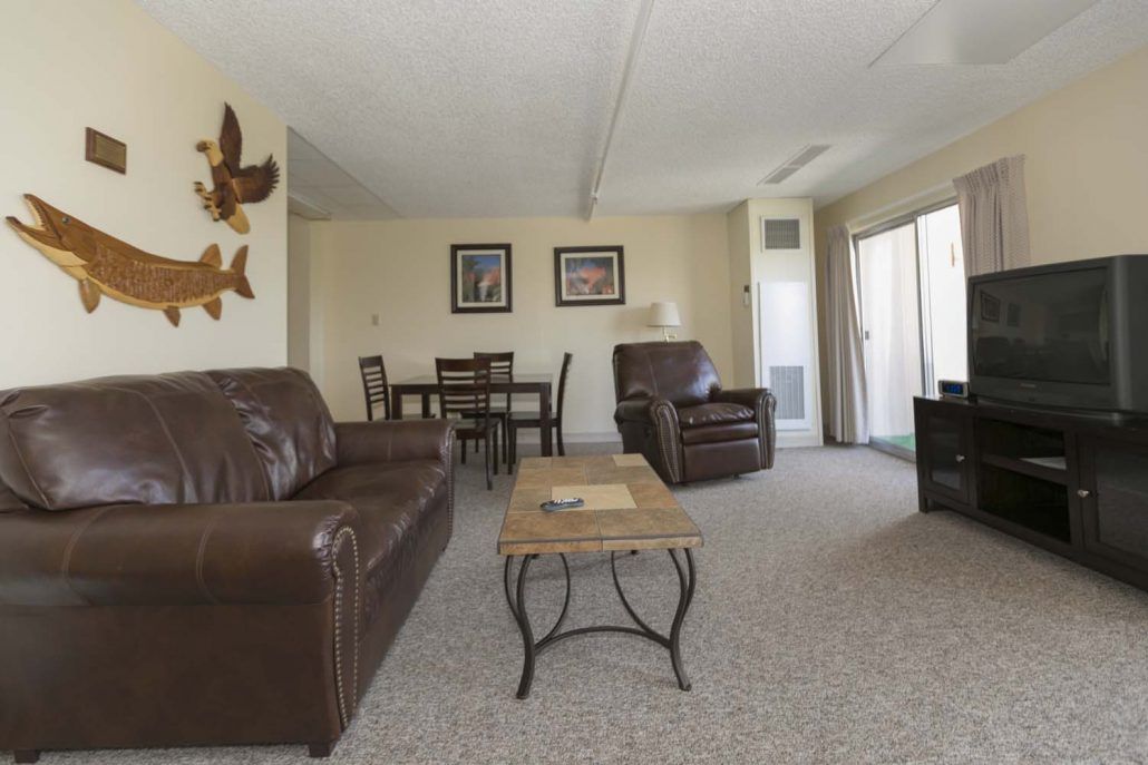 A cozy living room with a sofa, armchair, and a dining set.