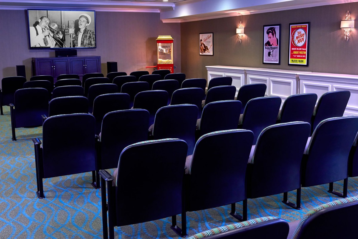 A small theater with rows of seats facing a screen, adorned with movie posters on the walls.