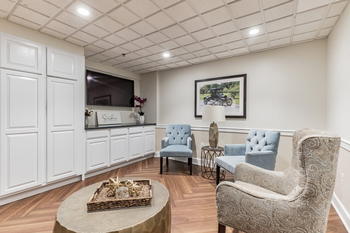 A cozy and modern seating area with elegant armchairs, a round coffee table, and stylish artwork on the wall.