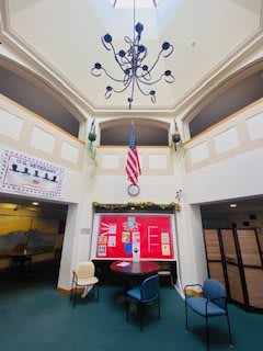 A modern lobby area featuring a chandelier, a red display board, and an American flag.