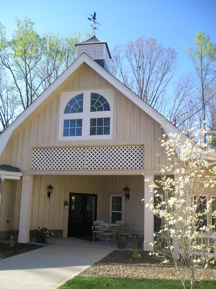 A quaint church building with a peaked roof, surrounded by budding trees in spring.