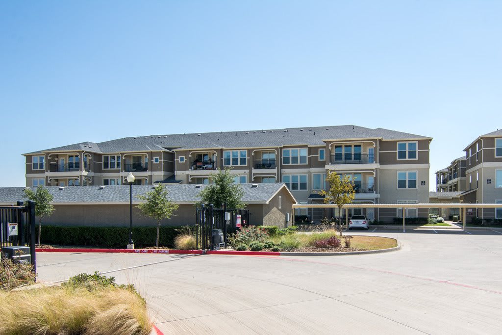A modern residential apartment building with a spacious parking area on a clear day.