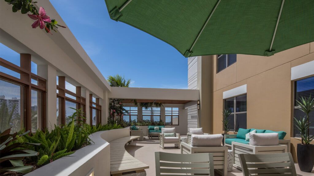 A sunny outdoor patio with seating and an umbrella.