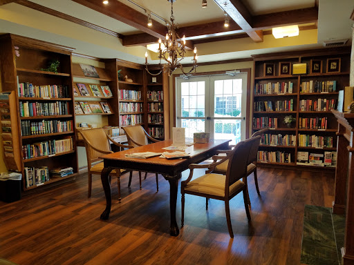 A warm and inviting library featuring wooden shelves filled with books, elegant lighting, and a comfortable reading area.