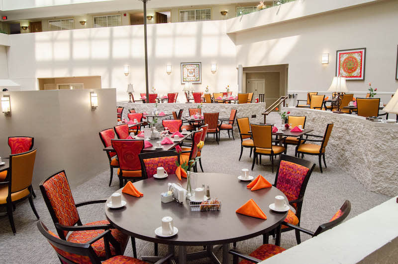 A bright and modern dining area with multiple tables and colorful chairs.
