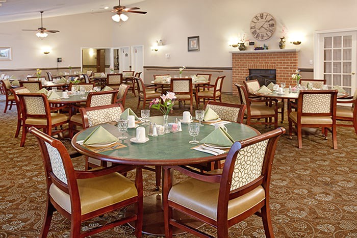 A cozy dining room setup with neatly arranged tables and chairs, featuring a warm ambiance and a fireplace.