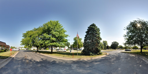 A serene park scene featuring lush green trees and a flag, under a clear blue sky.