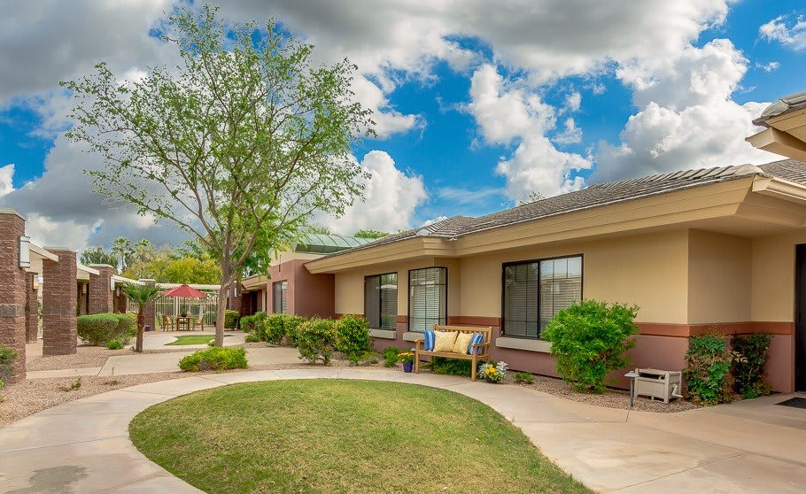 A lovely suburban home with a well-maintained garden and outdoor seating under a cloudy sky.