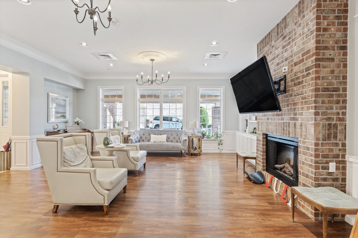 A spacious and elegantly designed living room with modern furnishings, a fireplace, and a large television.