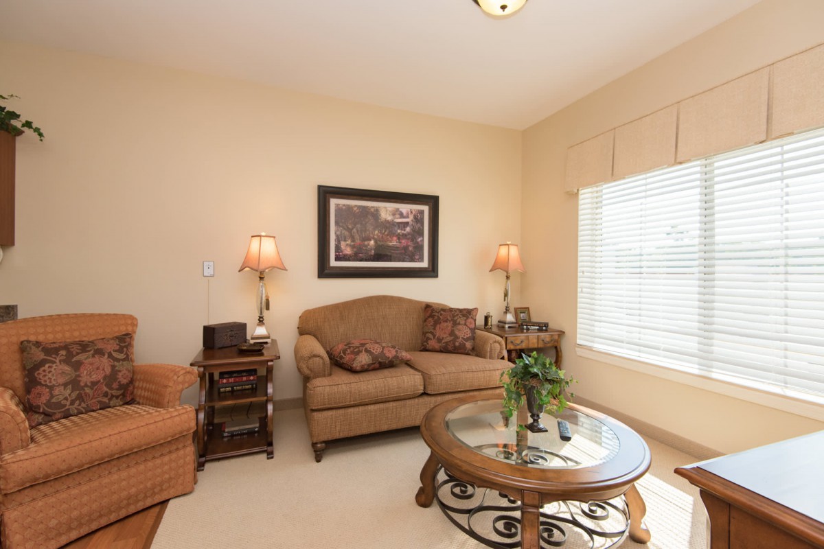 A cozy living room with a sofa, armchair, coffee table, and lamps.