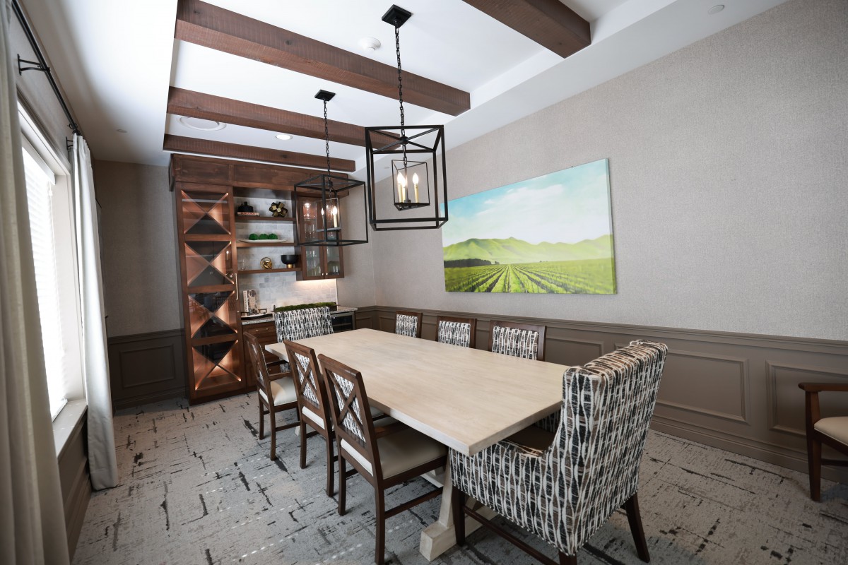 A modern dining room with wooden beams, a wine rack, and stylish furniture.
