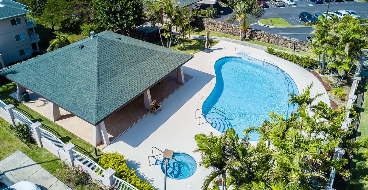Aerial view of a tropical outdoor swimming pool with a nearby pavilion.