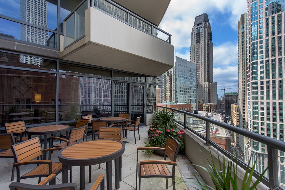 A spacious balcony with outdoor seating overlooking a vibrant city skyline.