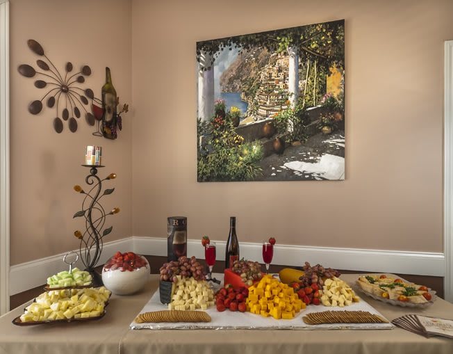 A beautifully arranged table with a selection of fruits, cheeses, and wine in an elegantly decorated room.