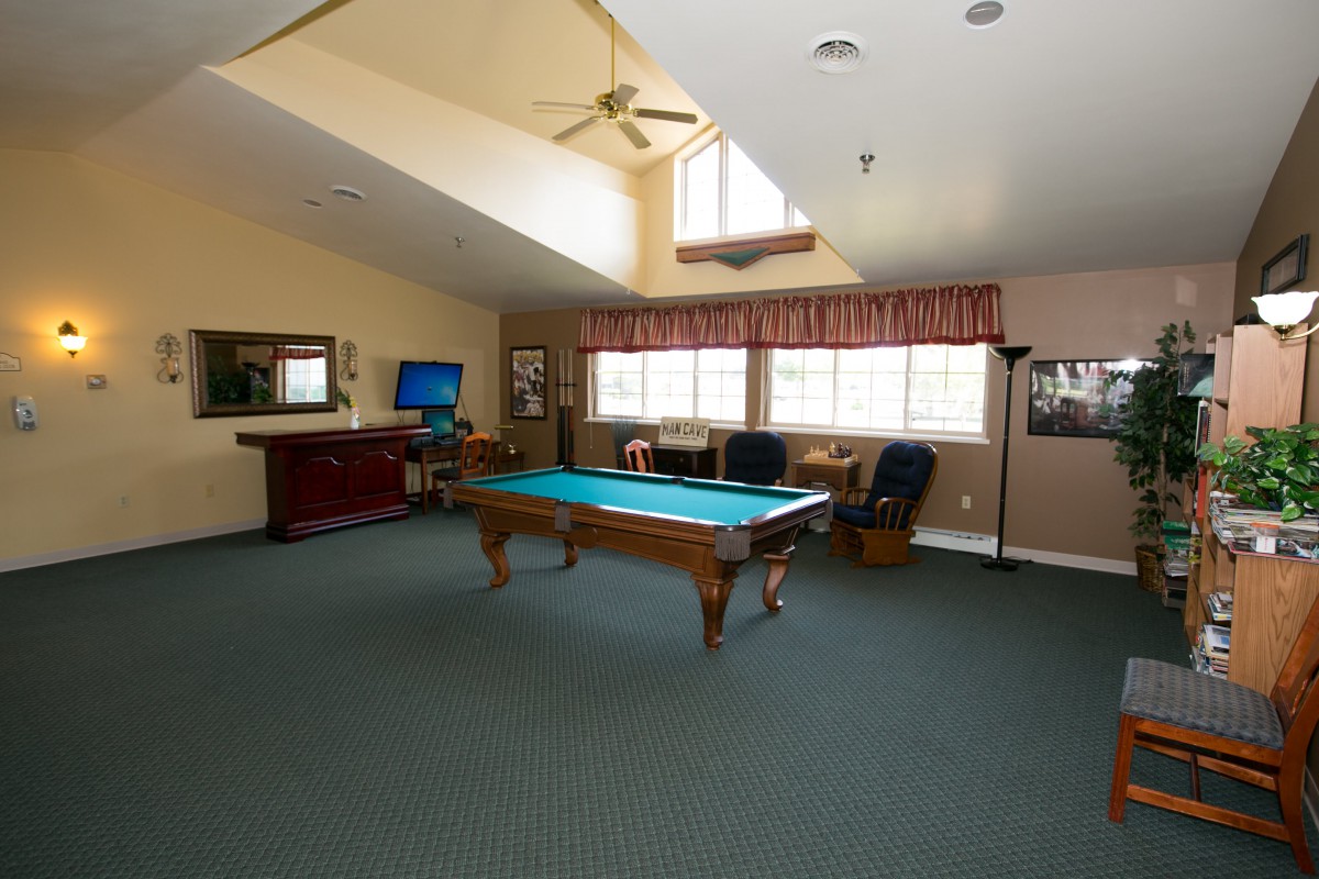 A spacious billiard room featuring a pool table, seating area, and entertainment options.