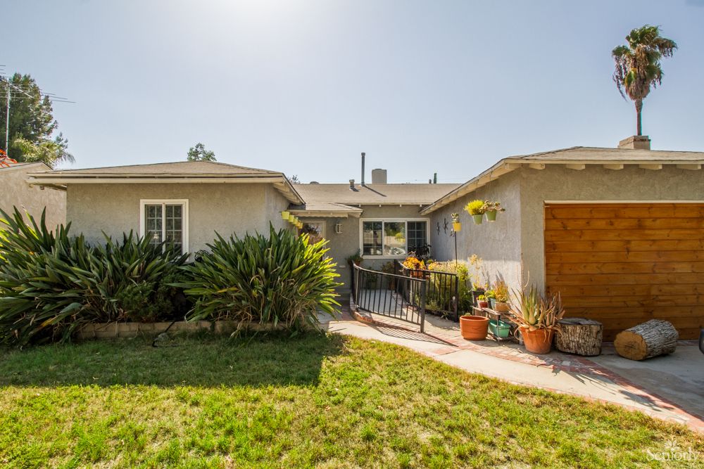 A cozy residential house with a well-maintained garden and sunny front yard.