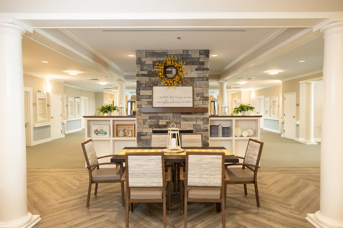 A well-lit interior dining area featuring a table with four chairs, set against a decorative brick wall.