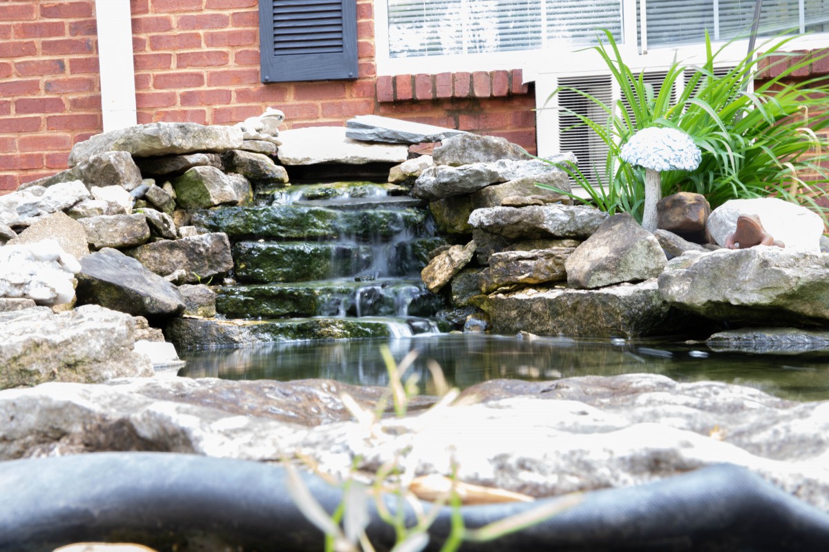 A small garden waterfall cascading over rocks into a pond.
