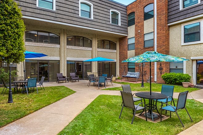 A cozy courtyard with outdoor seating and umbrellas at the back of a building.