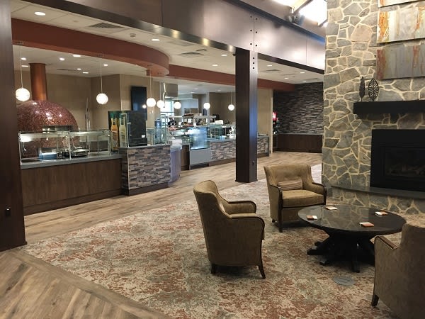 A modern lounge area with comfortable seating and a stone accent wall, adjacent to a cafe-style dining space.