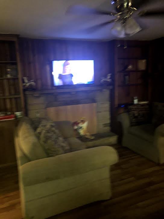 A cozy living room with a television mounted above a fireplace, surrounded by couches.