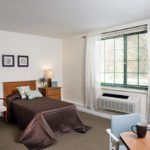 A cozy bedroom with a bed, dresser, and large window.
