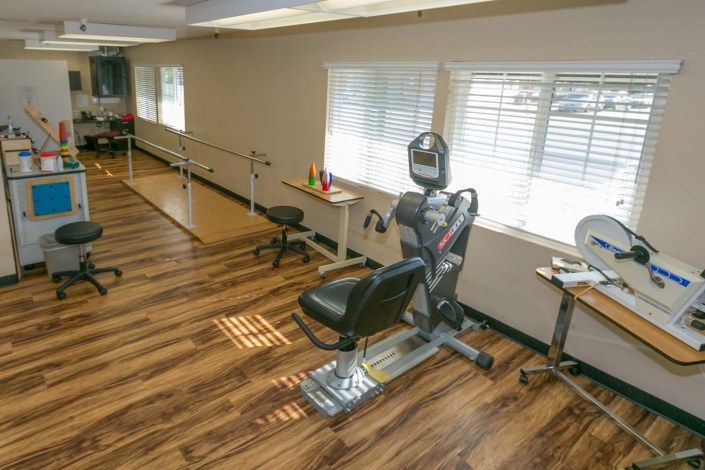 A therapy room equipped with exercise machines and parallel bars.