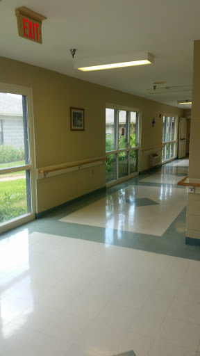 A well-lit hallway in a facility featuring large windows and clean flooring.