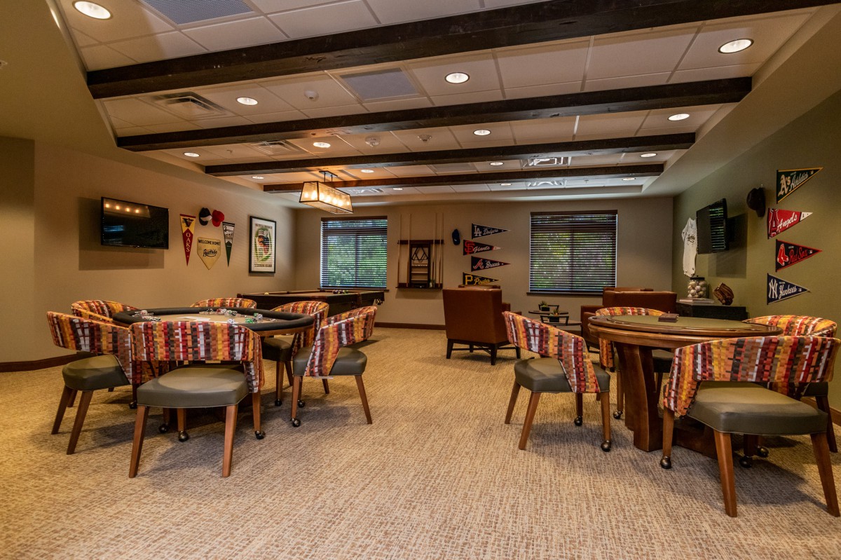 A cozy interior room with tables and chairs, warm lighting, and decorative elements on the walls.