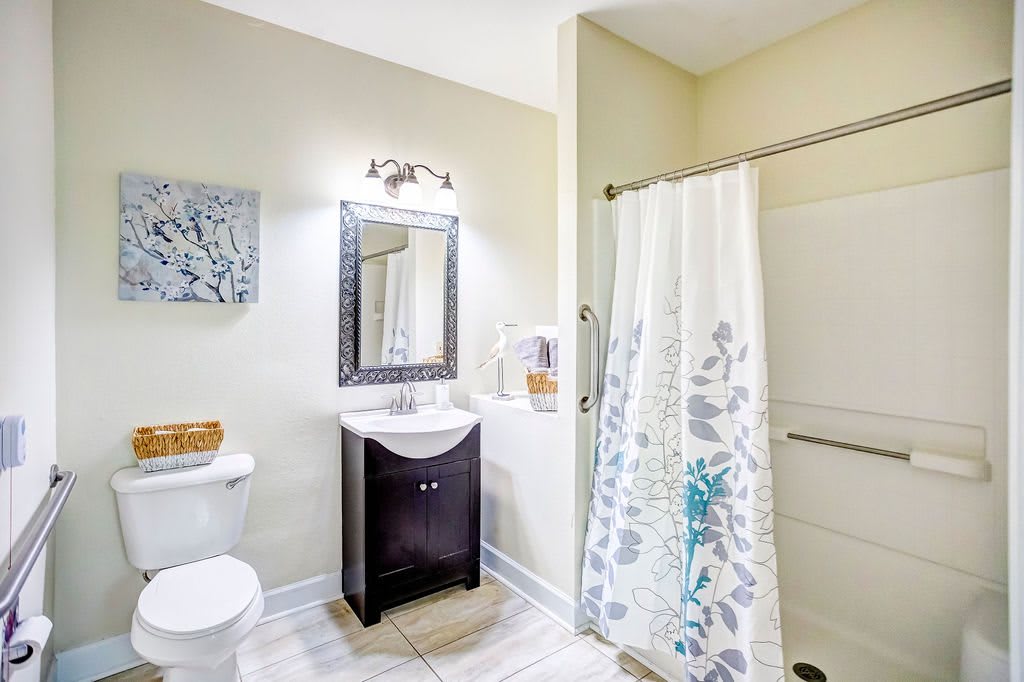 A modern bathroom with a stylish vanity, mirror, and floral shower curtain.