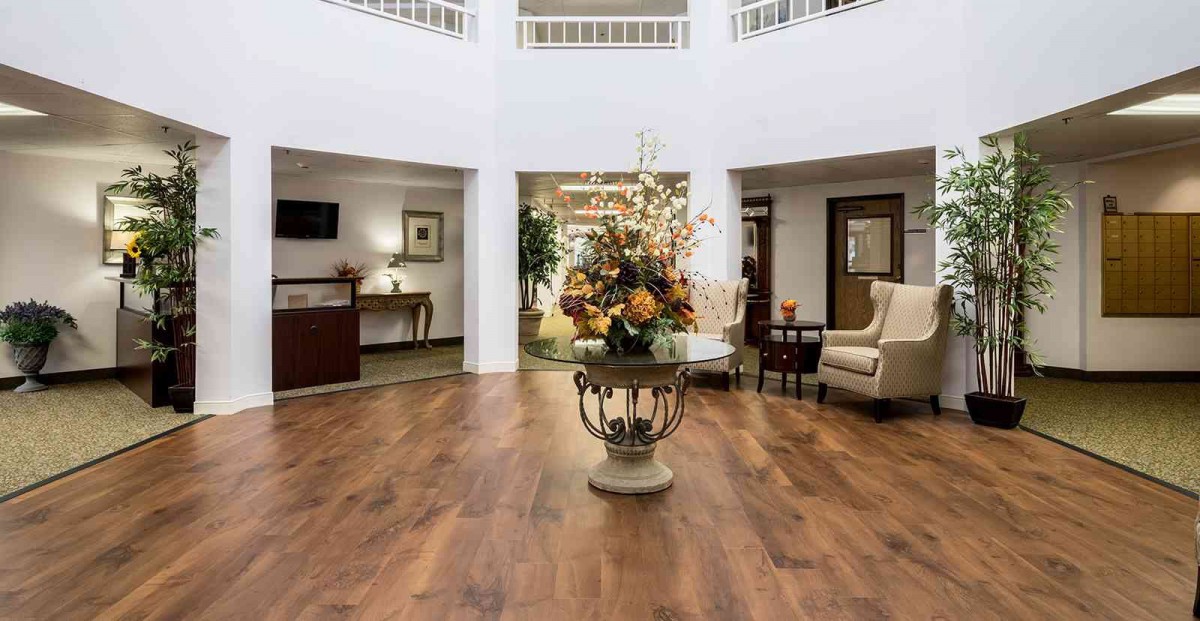A spacious and elegantly decorated lobby with wooden flooring and floral centerpiece.