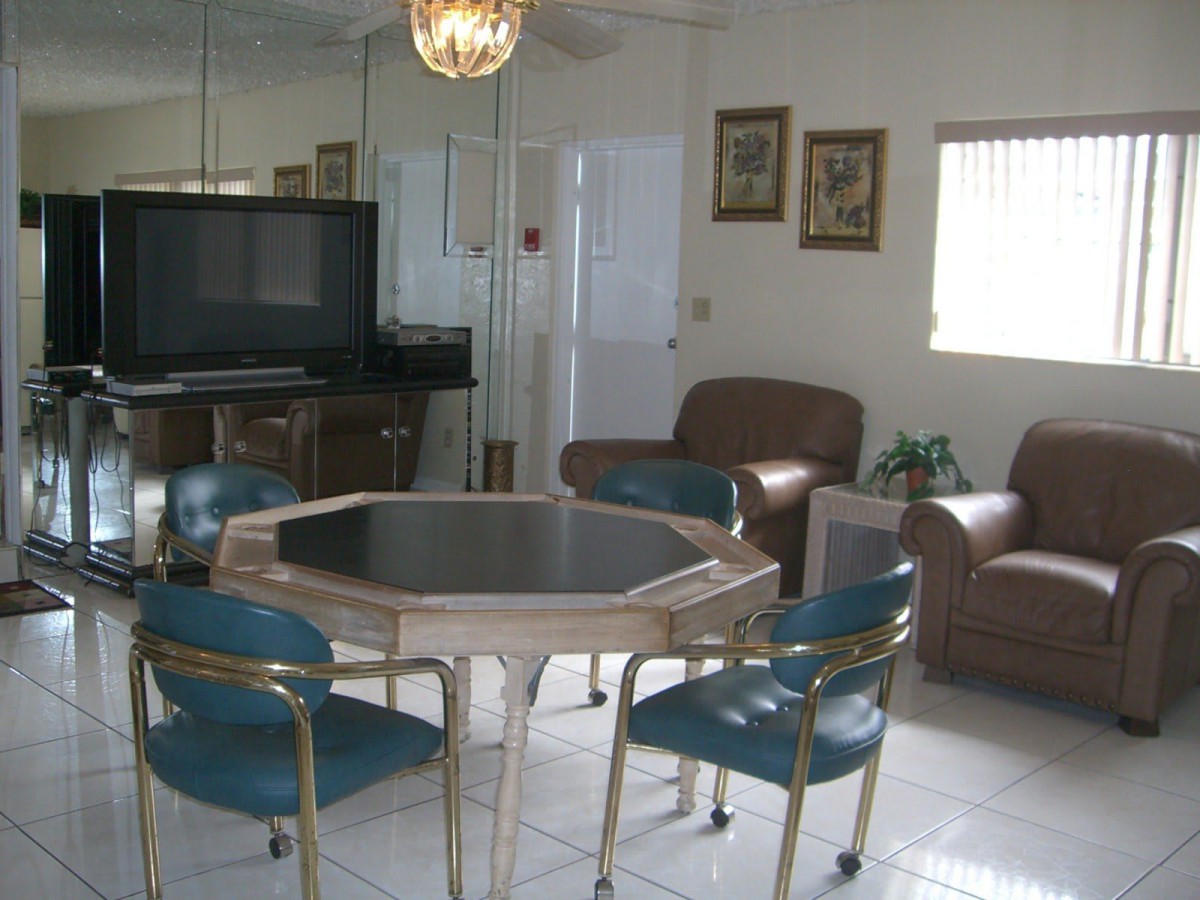 A cozy living room with a dining table and chairs, adjacent to a seating area with a television.