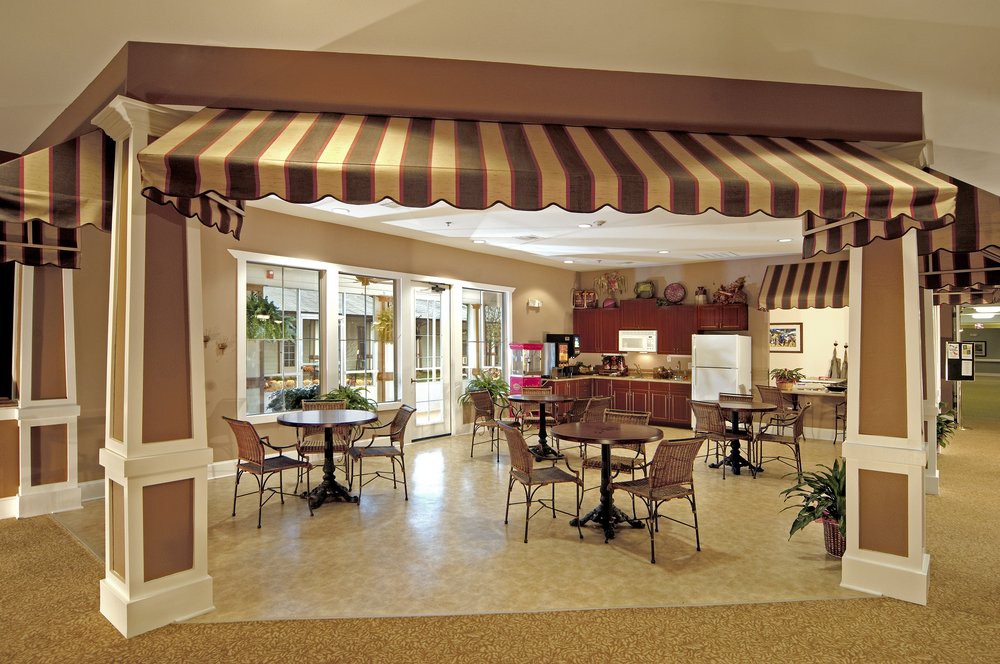 A cozy cafe interior with tables and chairs under a striped awning.