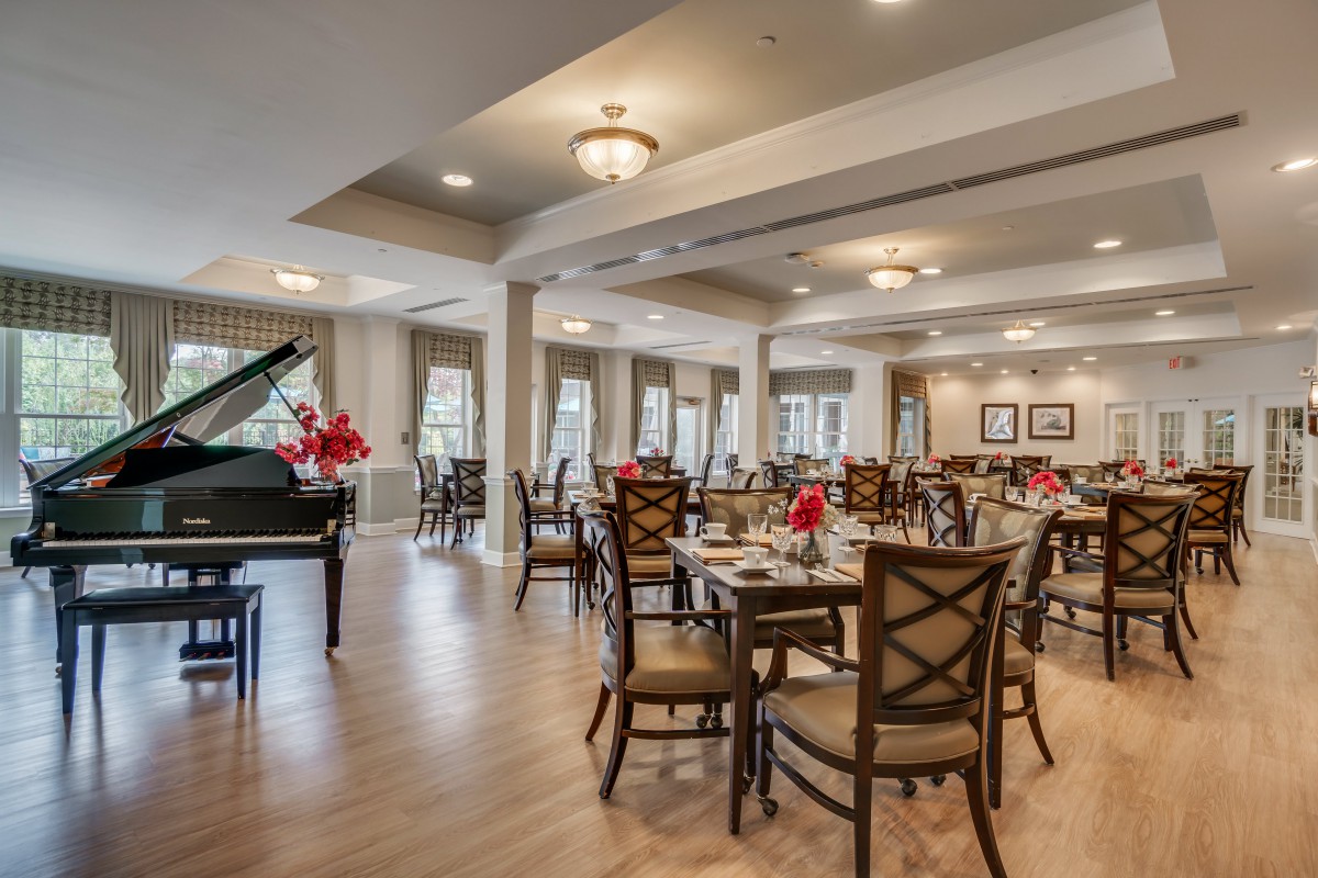 An elegant dining area featuring neatly arranged tables and a grand piano.