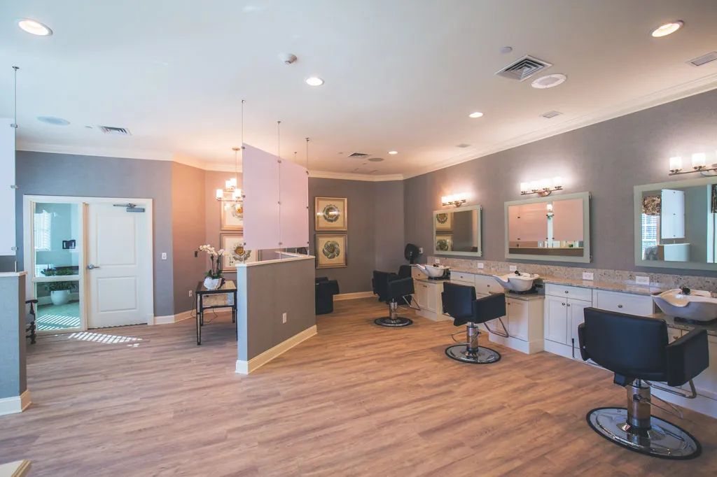 A modern hair salon with stylish chairs, mirrors, and wooden flooring.